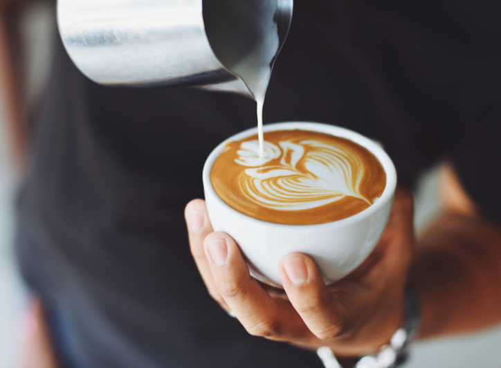 En kop kaffe bliver hældt over med mælk for at lave et blad af mælk