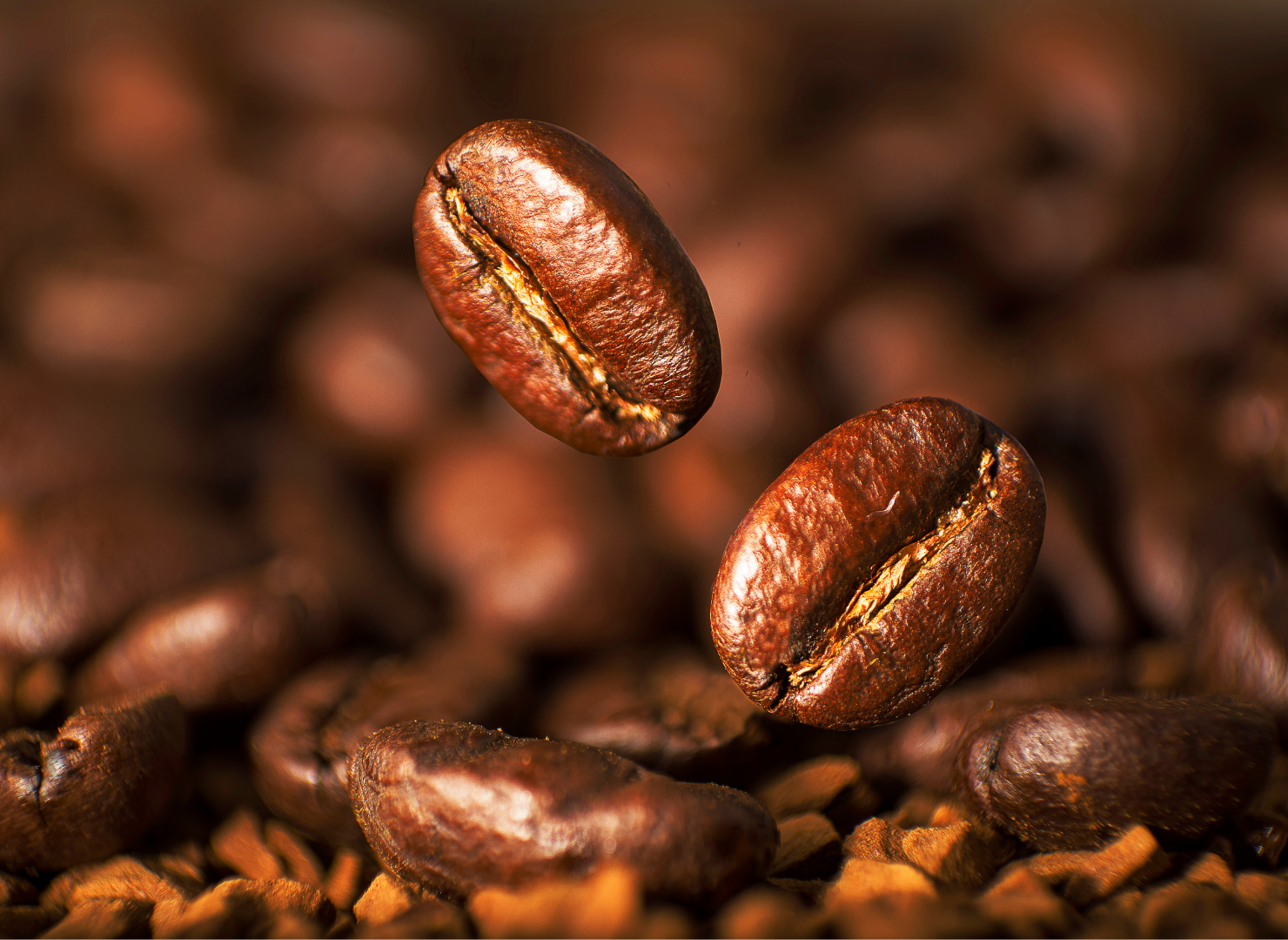 Kaffebønner falder ned og lander i kværnet kaffe.