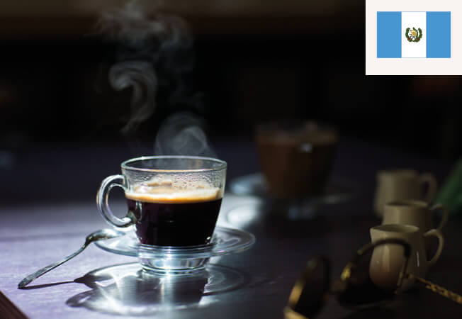 Kop espresso bord et bord med Guatemalas flag i højre hjørne