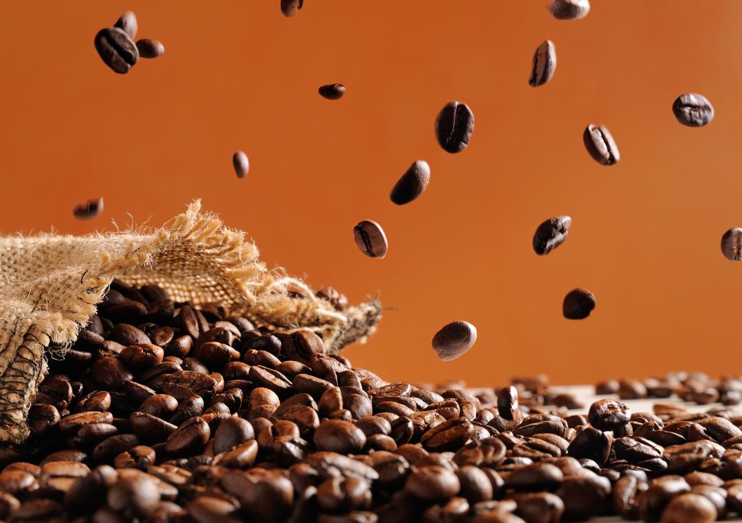 En pose fyldt med kaffebønner hældes ud på et bord.