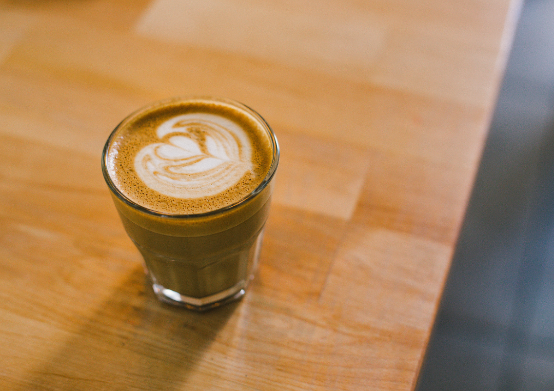 Flat white i et glas på et træbord