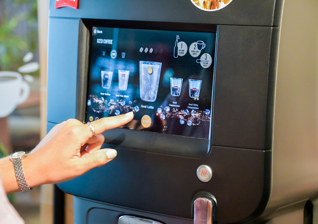 Person vælger en kaffedrik på en kaffemaskine