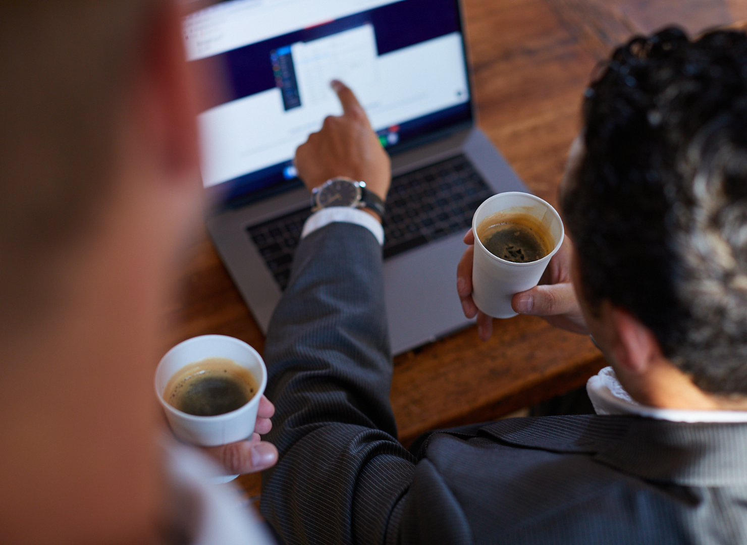 Mand sidder ved computer og en kop kaffe i hånden