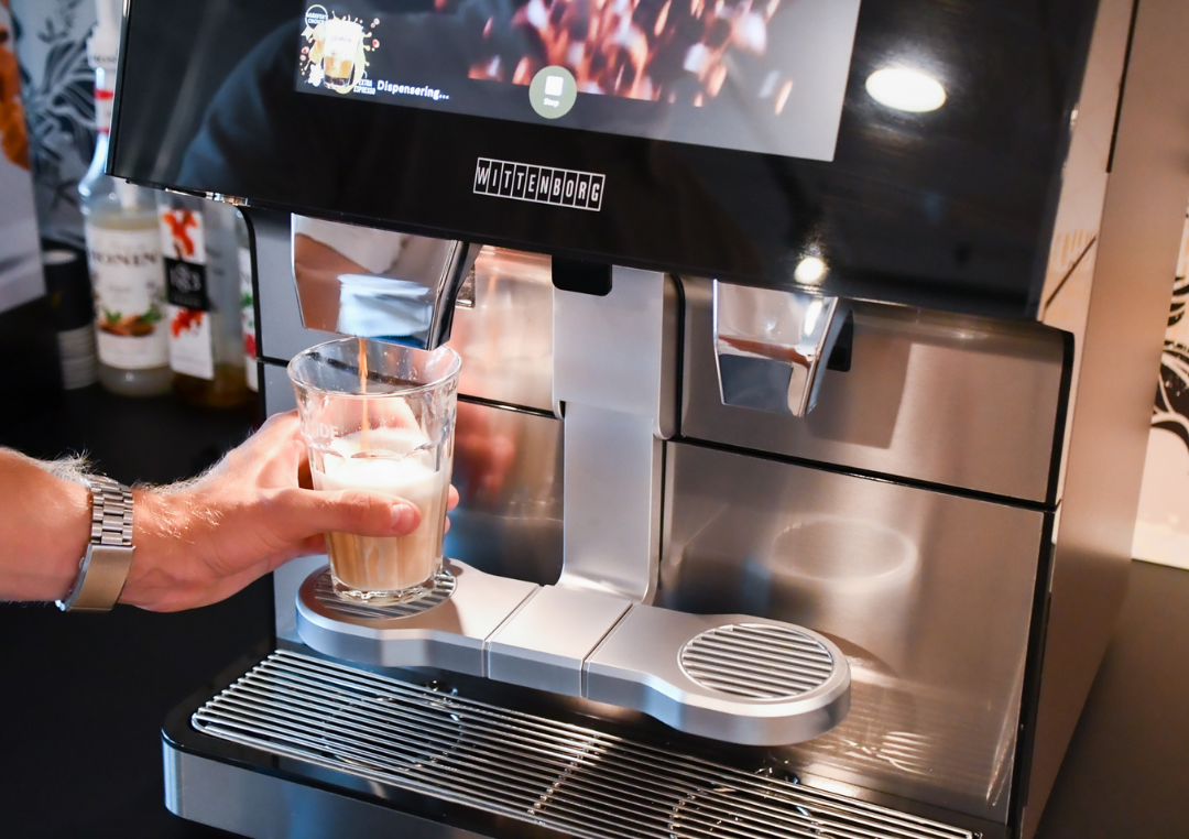 Glas fyldes med kaffe latte på en kaffemaskine