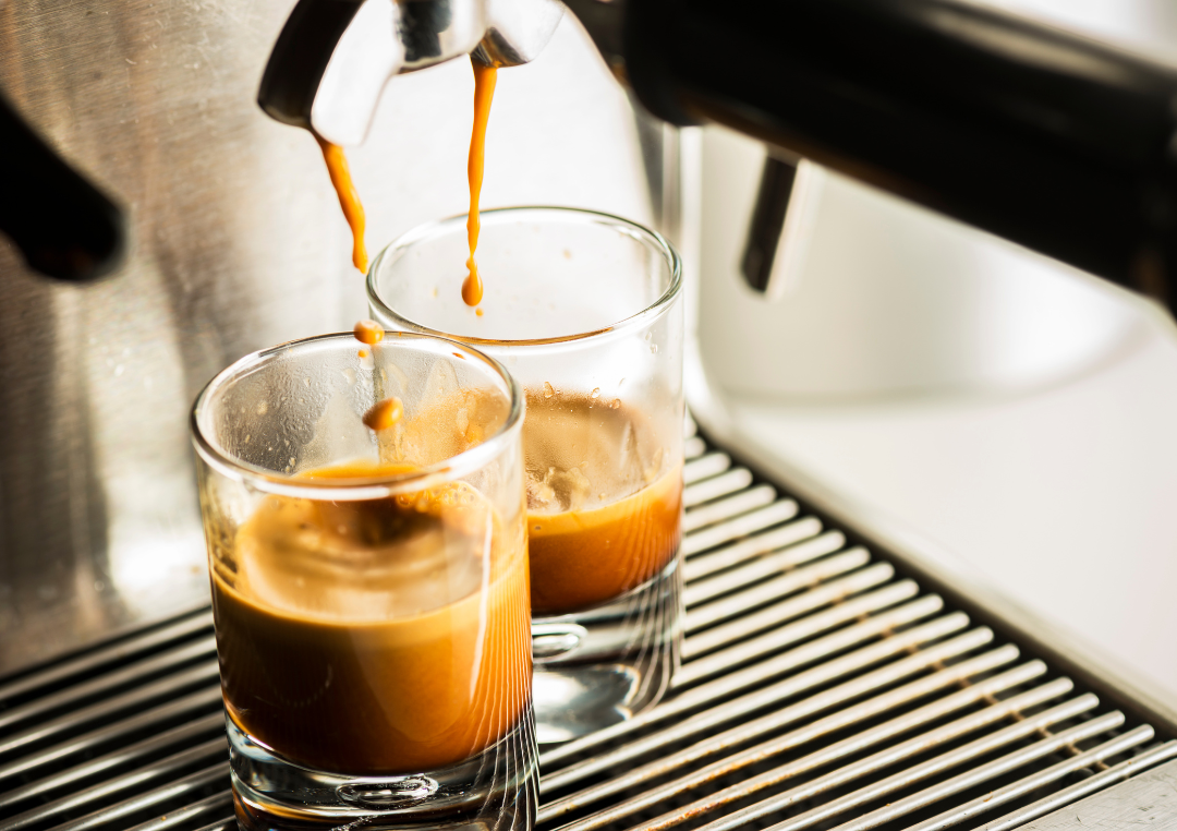 2 glas bliver fyldt med epsresso fra en maskine.