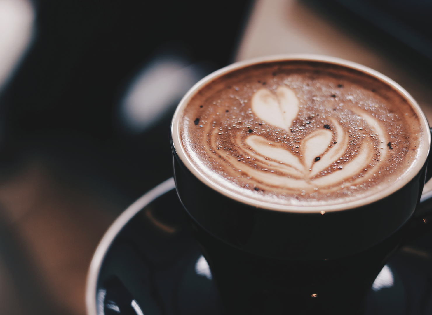 En mand står ved en kaffekværn og holder nogle kaffebønner i hånden.