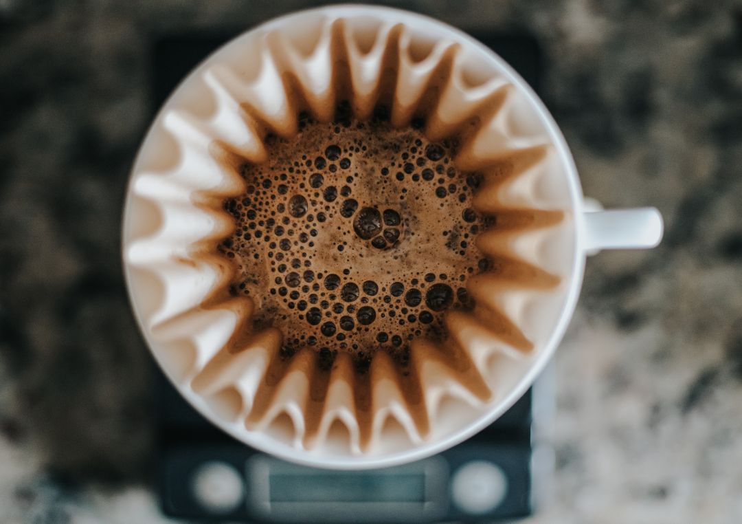 En kop med kaffefilter fyldt med sort kaffe set oppe fra.